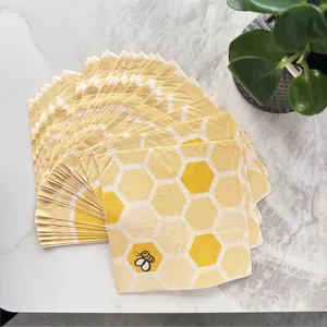 Vista detallada de servilletas amarillas con patrón de panal y una pequeña abeja ilustrada