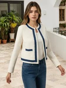 Detailansicht der cremefarbenen Kurzjacke im Tweed-Stil mit blauem Fransenbesatz
