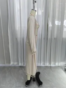 Detailed side profile view of a beige long-sleeved cardigan featuring tassel lace trim.