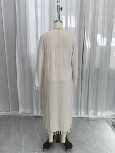 Full back view of a beige long sleeve beach cover-up with bohemian tassel fringe trim.