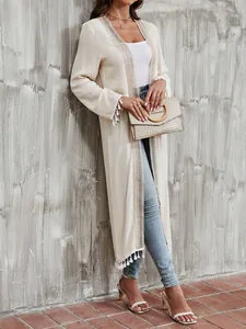 Detail of cream long beach cover-up with delicate lace trim and bohemian tassels