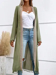 Close-up detail of women's olive green beach cover-up with tassel fringe and lace trim