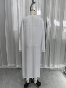 Detail view of a white long-sleeved beach cover-up with tassel trim on mannequin