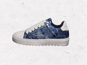 Vista lateral de zapatilla de mezclilla azul con suela blanca gruesa y detalle de pintura.