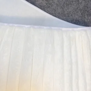 Detailed macro shot of white plush Christmas tree skirt with vertical stitched stripes.