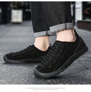 Vue latérale détaillée de chaussures de randonnée en daim noir pour hommes sur un trottoir