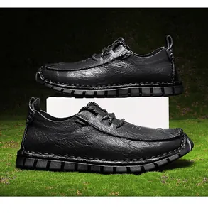 Macro view of black textured leather casual men's shoes on green grass backdrop