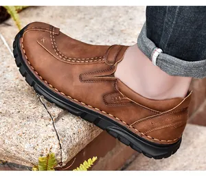 Detailweergave van bruine herenleren loafers met witte handgestikte decoratieve details