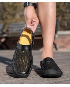 Detail van ademende zwarte mesh clogs voor heren met antislip gele binnenzool en design.