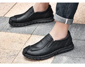 Detail van zwarte herenlederen loafers met handgestikte naden op een stenen vloer