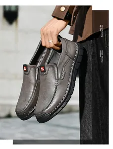 Detailansicht der handgenähten grauen Leder-Slipper, die draußen in der Hand gehalten werden