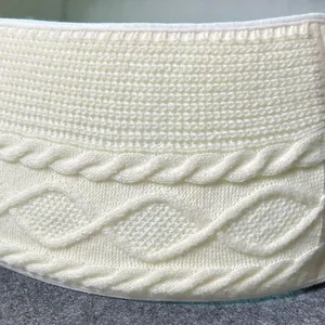Close-up detail of white knitted Christmas tree skirt showing cable knit texture.
