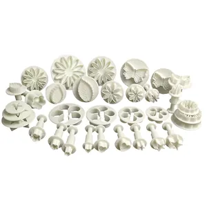 Close-up of 33-piece white plastic fondant plunger cutter set with floral and star shapes