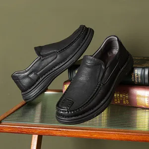 Detailed side view of black leather slip-on loafers displayed on books and glass table