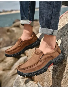 Close-up view of men's brown nubuck leather slip-on outdoor work shoes on rocks