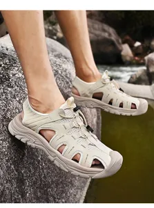 Detail of breathable men's closed-toe outdoor sports sandals in beige on a rock