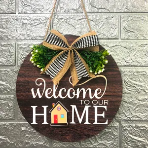 Detailed view of a round wooden welcome home door sign with burlap bow and foliage.