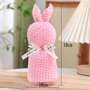 Asciugamano in pile corallo rosa piegato come regalo a coniglio con nastro di perle