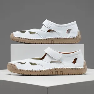 Side detail of white hollow-out leather nurse sandals with brown rubber soles.