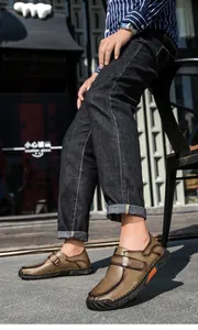 Dichtbij van bruine handgestikte leren loafers gedragen met donkere jeans voor casual look