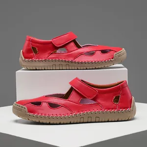 Detailed macro view of vibrant red leather hollowed-out sandals with durable rubber soles
