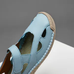Detailed macro view of light blue genuine leather hollow-out loafers with white stitching.