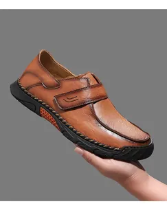 Detailopname van bruine leren herenloafers met handgemaakte stiksels en band