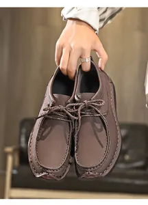 Detail van bruine lederen mocassins met veters, met de hand vastgehouden
