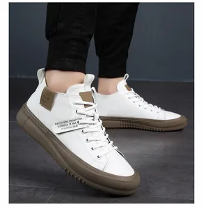 Dettaglio ravvicinato delle sneakers alte in pelle bianca da uomo con suole in gomma marrone.