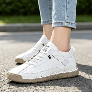 Close-up of white hand-stitched casual sneakers featuring beige rubber soles