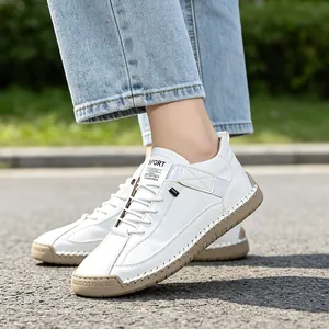 Close-up of white casual men's shoes with brown rubber sole and visible stitching.