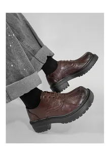 Nahaufnahme von Vintage-Oxford-Schuhen aus braunem Leder mit dicker Sohle und Nähten am Fuß.