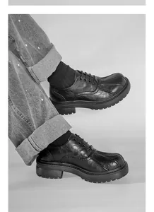 Detailansicht schwarzer Retro-Lederschuhe mit dicker Sohle und Schnürung am Fuß.