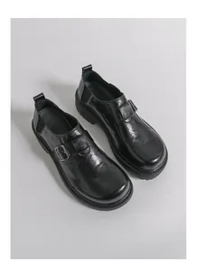 Detailansicht von schwarzen Retro-Leder-Loafers mit Metallschnalle und robuster dicker Sohle