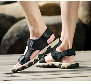 Detailaufnahme schwarzer Outdoor-Sandalen für Herren mit Klettverschluss auf Holzdeck