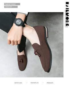Detail view of men's brown suede loafers featuring elegant double tassels and pointed toe