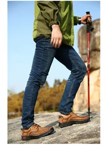 Close-up of men's brown leather outdoor hiking shoes in a natural mountain setting.