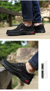 Detail view of black men's outdoor leather shoes with rugged hiking soles on a wooden path.