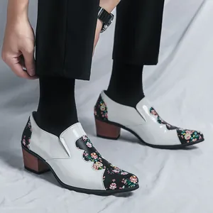 Stylish men's white patent leather shoes with floral stitching and wood grain block heels.
