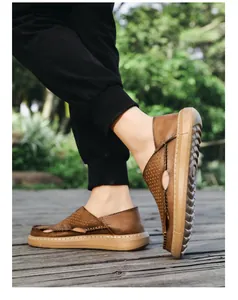 Detailansicht der atmungsaktiven braunen Herren-Leder-Slipper auf einem Holzweg