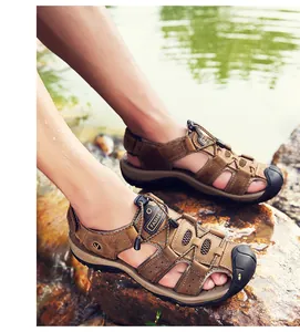 Gedetailleerde close-up van bruine outdoor wandelsandalen voor heren op rotsen aan de rivier