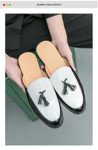 Detail showing men's black and white patent leather loafers with tassels held by hand.