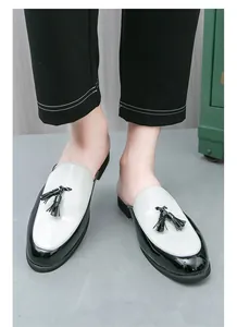 Close-up view of stylish black and white patent leather mules with tassel decoration