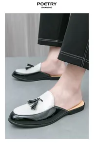 Close-up detail of stylish men's black and white patent leather tassel mules