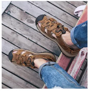Close-up van heren leren outdoorsandalen met stootvaste neus op een houten vloer.