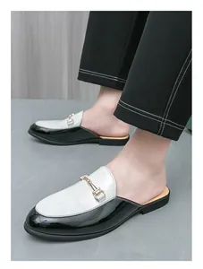 Detail of men's black and white patent leather loafers with gold buckle.