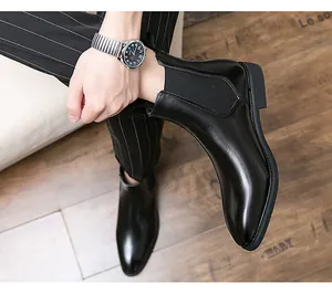 Close-up detail of elegant polished black leather Chelsea boots worn with classic striped pants