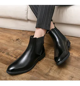 Close-up detail of glossy black leather men's Chelsea boots on wood floor