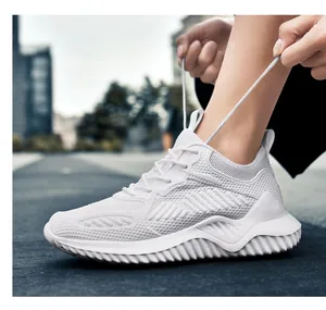 Witte ademende fly-knit mesh casual sportsneakers getoond in een buitenomgeving