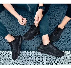 Close-up van zwarte ademende mesh-sneakers gedragen door een stel op een tegelvloer.